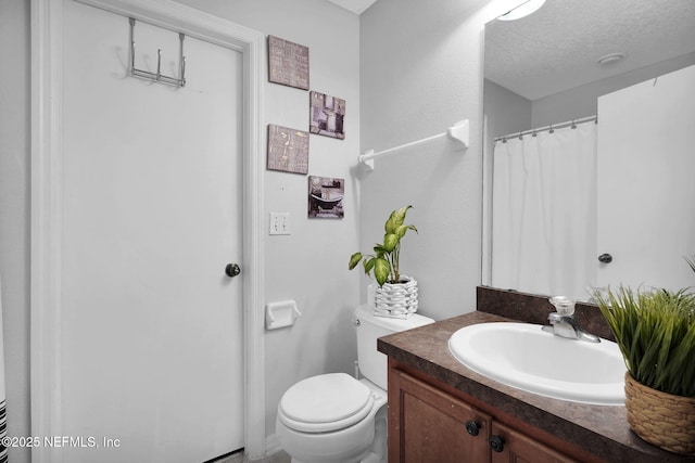 bathroom with vanity, toilet, and a textured ceiling