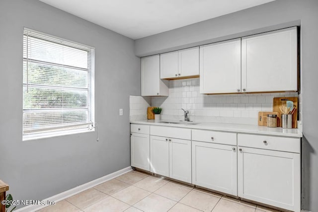 kitchen with sink, white cabinets, tasteful backsplash, and light tile patterned floors