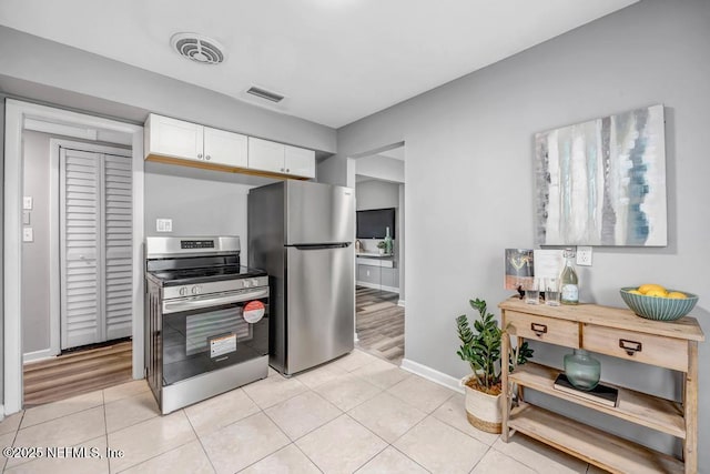 kitchen with white cabinets, light tile patterned floors, and stainless steel appliances