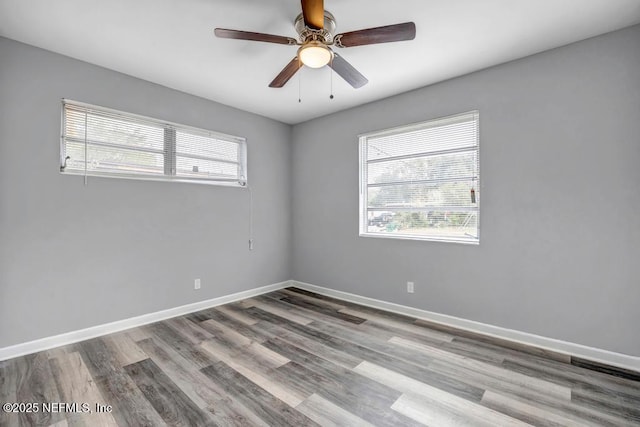 empty room with ceiling fan, a wealth of natural light, and light wood-type flooring