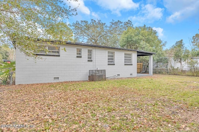 rear view of property with central air condition unit and a lawn