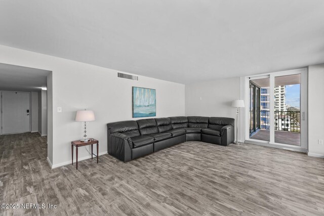 living area featuring baseboards, visible vents, and wood finished floors