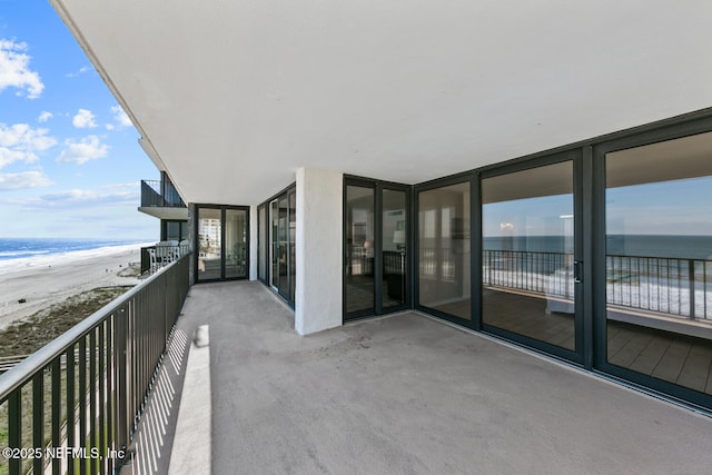 balcony with a view of the beach, a sunroom, and a water view