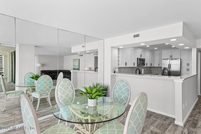 dining space with light wood finished floors, visible vents, and recessed lighting