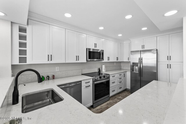 kitchen featuring recessed lighting, stainless steel appliances, a sink, white cabinets, and light stone countertops