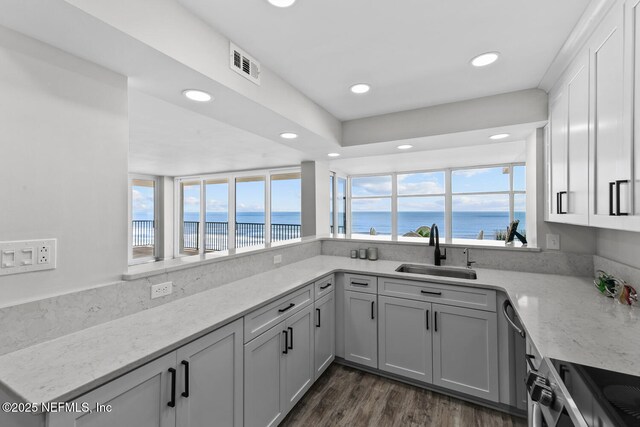 kitchen featuring light stone countertops, stainless steel electric range, visible vents, and a sink