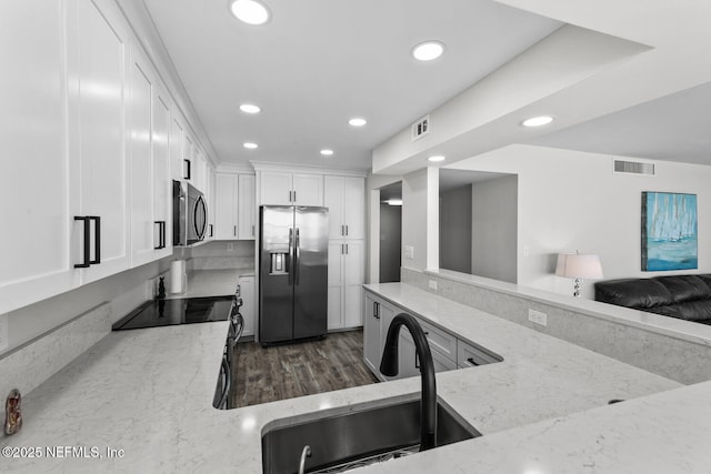 kitchen featuring appliances with stainless steel finishes, visible vents, a sink, and light stone countertops