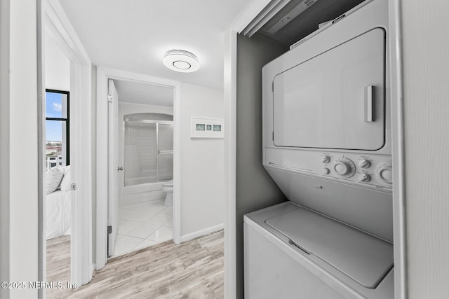 clothes washing area with laundry area, stacked washer / dryer, and wood finished floors