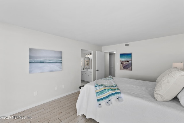 bedroom with visible vents, light wood-style floors, a sink, ensuite bath, and baseboards