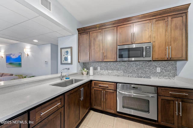 kitchen featuring appliances with stainless steel finishes, a sink, visible vents, and tasteful backsplash