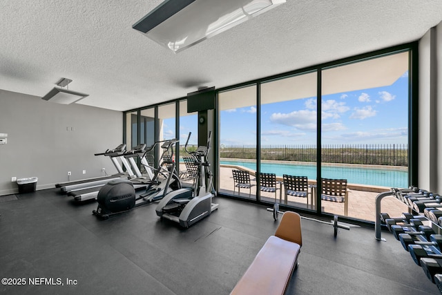 gym featuring baseboards, a wall of windows, and a textured ceiling