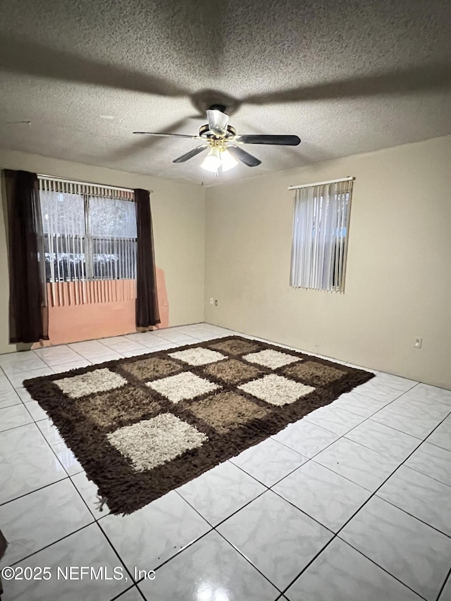 empty room with ceiling fan and a textured ceiling