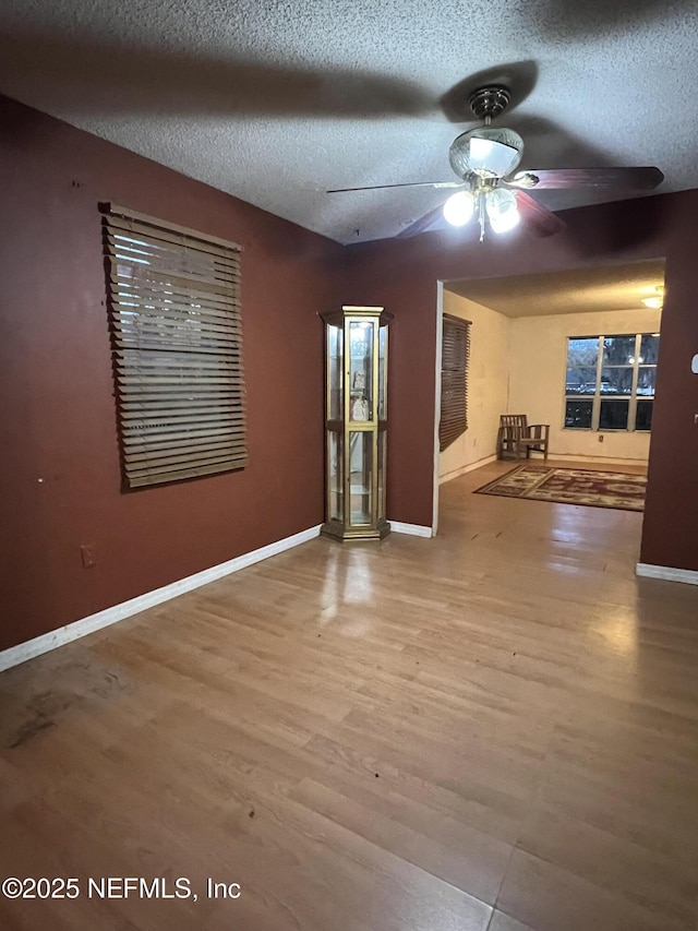 unfurnished room with light wood-type flooring, a textured ceiling, and ceiling fan