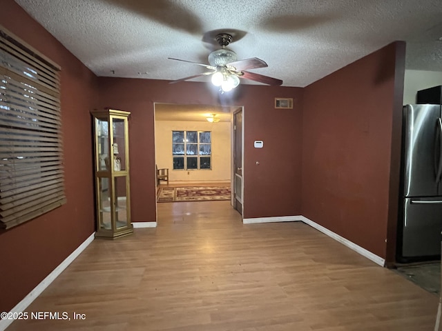 interior space with light wood-type flooring, ceiling fan, and a textured ceiling