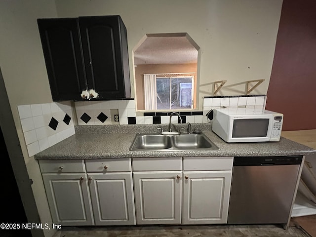 kitchen featuring decorative backsplash, sink, white cabinets, and dishwasher