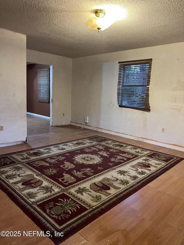 unfurnished room with hardwood / wood-style floors and a textured ceiling