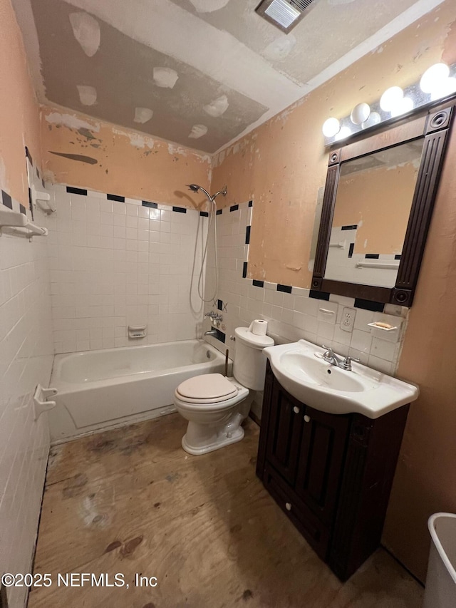 full bathroom featuring vanity, toilet, tile walls, and tiled shower / bath combo