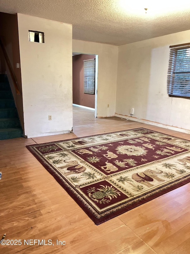 empty room with wood-type flooring and a textured ceiling