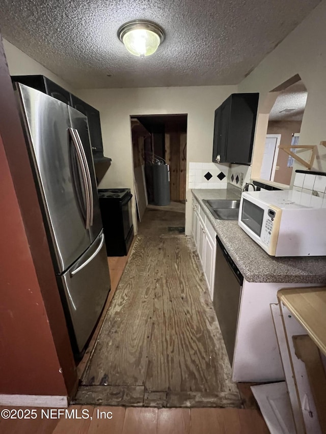 kitchen with sink, a textured ceiling, stainless steel appliances, and light wood-type flooring