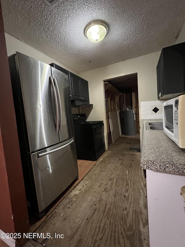 kitchen featuring black range with electric cooktop, hardwood / wood-style floors, a textured ceiling, and stainless steel refrigerator