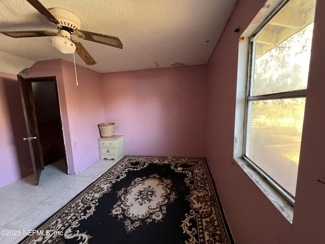 interior space with ceiling fan and a textured ceiling