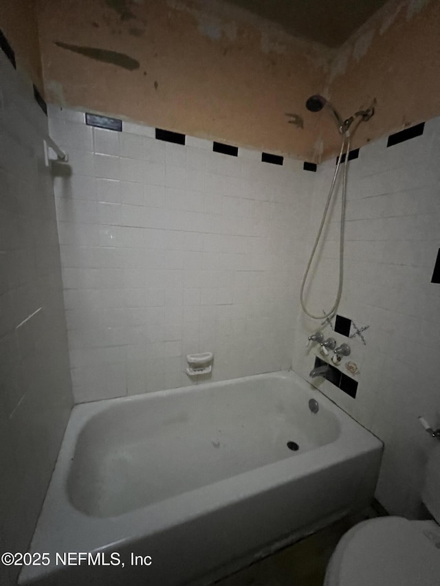 bathroom with toilet and tiled shower / bath