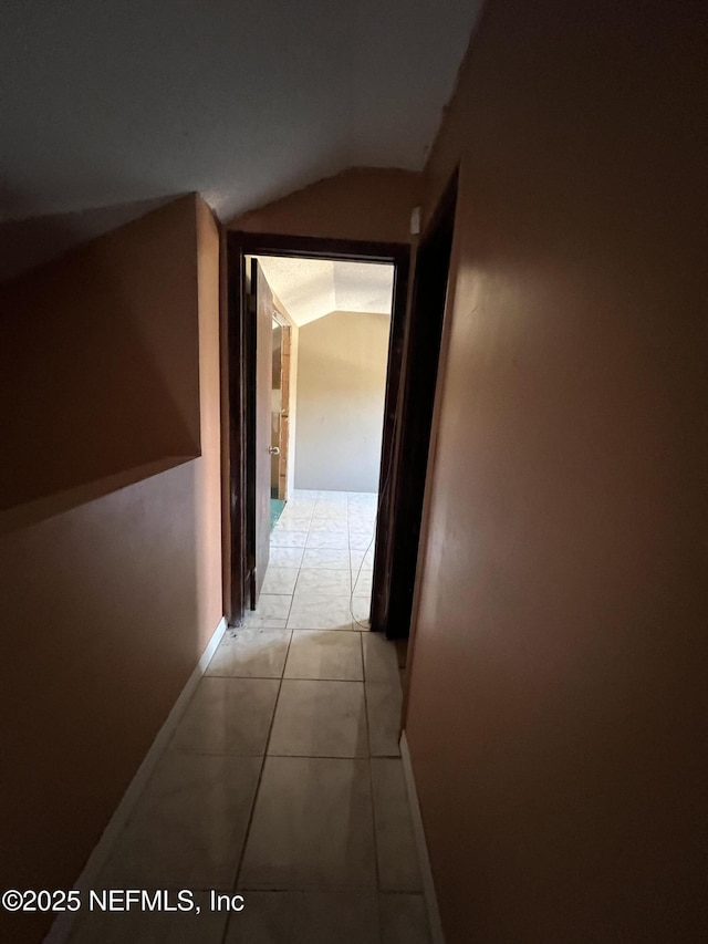 hallway featuring light tile patterned floors and lofted ceiling