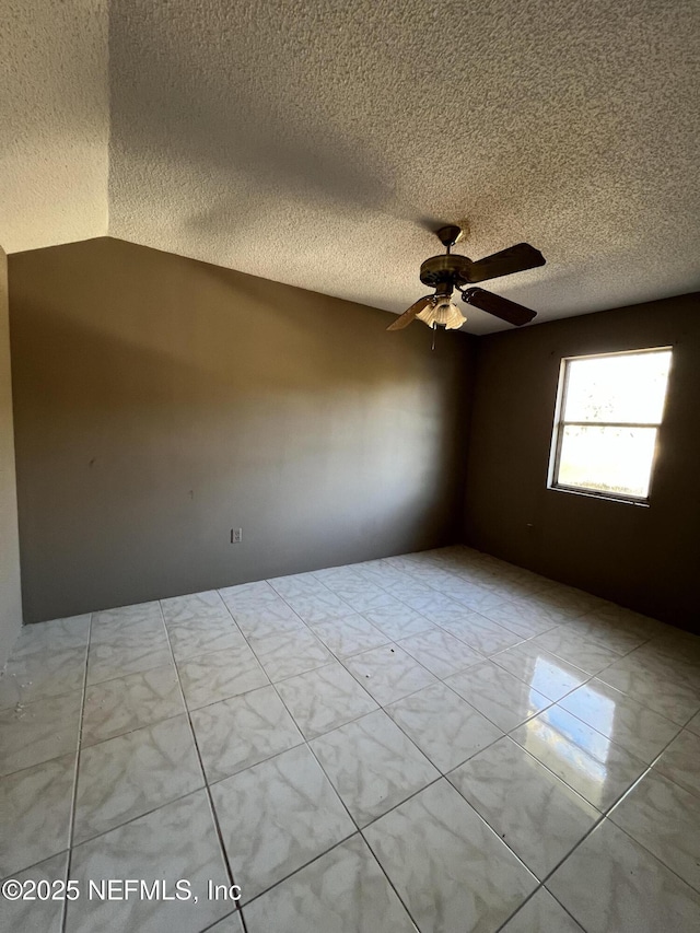 empty room featuring ceiling fan, a textured ceiling, and lofted ceiling