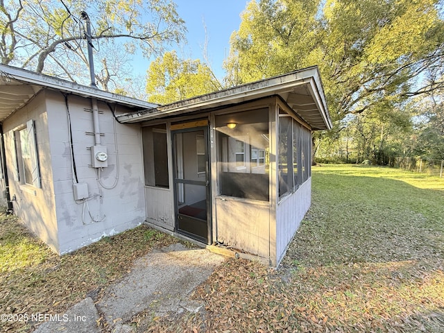 view of outdoor structure featuring a sunroom and a lawn