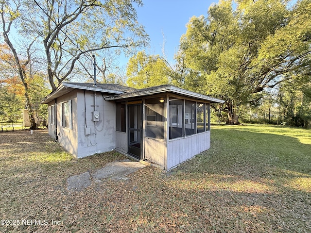 view of outdoor structure with a lawn and a sunroom