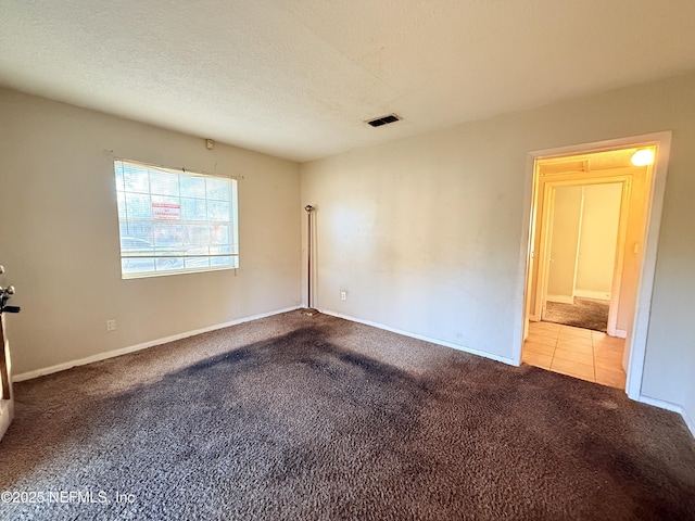 empty room with carpet flooring and a textured ceiling