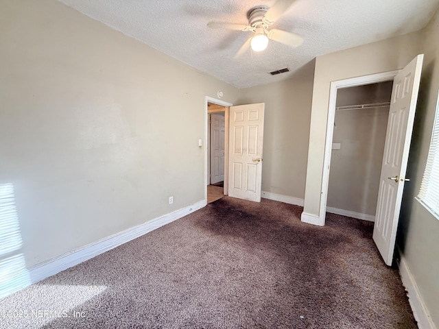 unfurnished bedroom with a closet, ceiling fan, dark colored carpet, and a textured ceiling