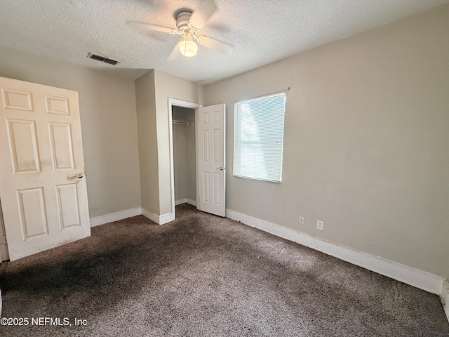 unfurnished bedroom featuring ceiling fan, dark carpet, a closet, and a textured ceiling