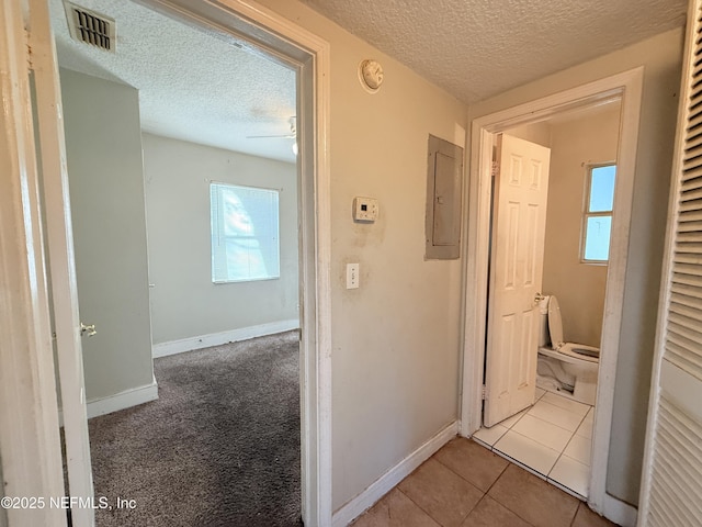 hallway with a wealth of natural light, light tile patterned floors, and a textured ceiling