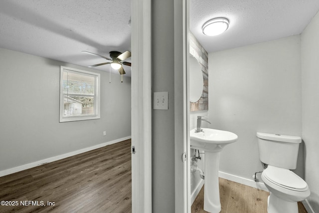 bathroom with toilet, sink, wood-type flooring, a textured ceiling, and ceiling fan