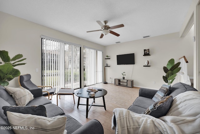 living room with a textured ceiling, light hardwood / wood-style floors, and ceiling fan