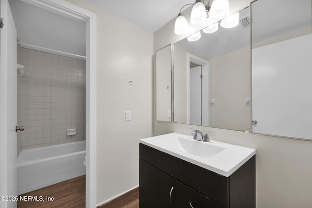 bathroom with wood-type flooring, tiled shower / bath combo, and vanity