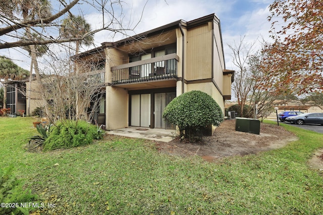 rear view of property featuring a balcony and a yard