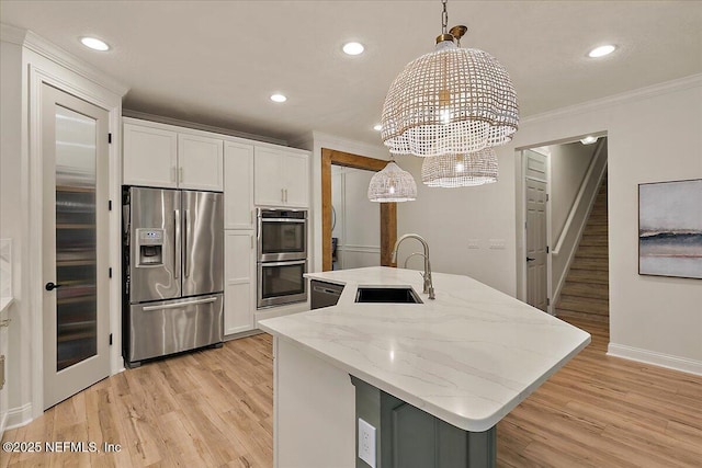 kitchen featuring white cabinetry, hanging light fixtures, stainless steel appliances, and a center island with sink