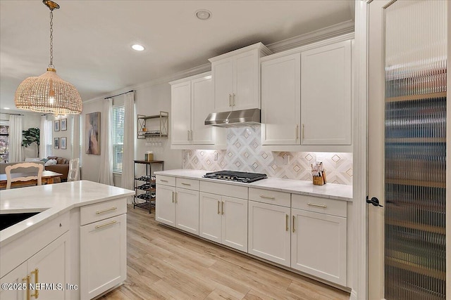 kitchen featuring pendant lighting, stainless steel gas stovetop, white cabinets, decorative backsplash, and light hardwood / wood-style flooring