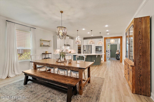 dining space with ornamental molding, an inviting chandelier, a textured ceiling, and light wood-type flooring