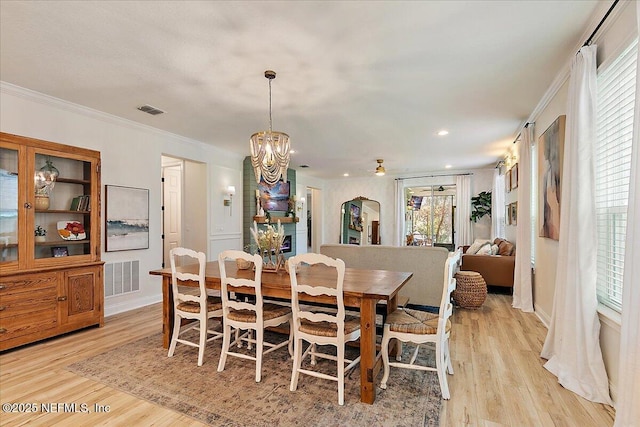 dining room featuring light hardwood / wood-style flooring, ornamental molding, and a chandelier