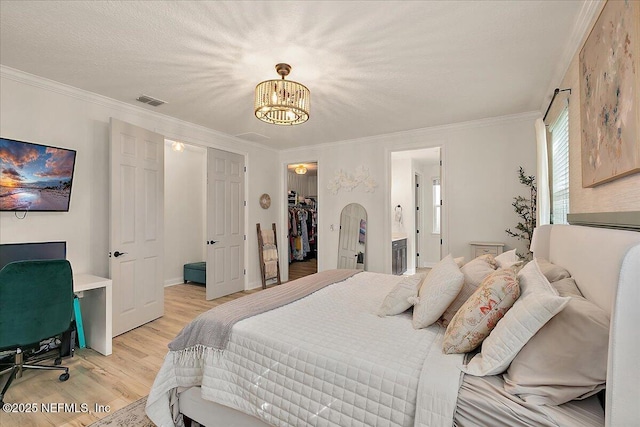 bedroom featuring ornamental molding, a spacious closet, ensuite bathroom, and light wood-type flooring