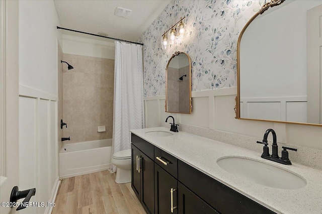 full bathroom with toilet, a textured ceiling, vanity, shower / bath combo with shower curtain, and hardwood / wood-style floors