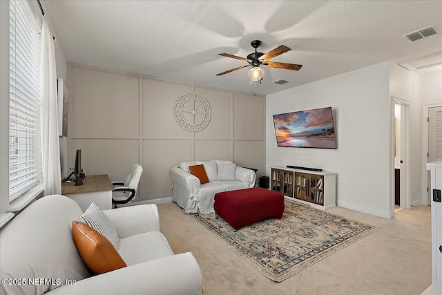 carpeted living room featuring ceiling fan, a wealth of natural light, and a textured ceiling