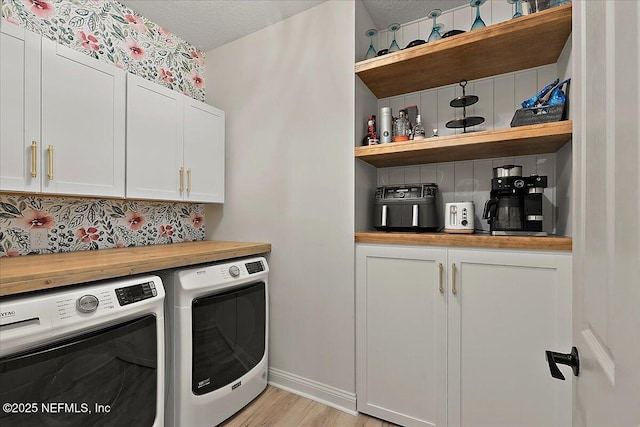 laundry area with cabinets, washer and dryer, a textured ceiling, and light wood-type flooring