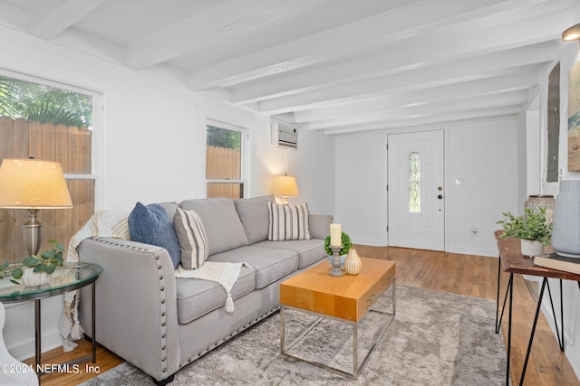 living room featuring light hardwood / wood-style floors, an AC wall unit, and beam ceiling