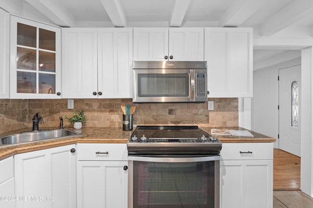 kitchen featuring sink, white cabinetry, appliances with stainless steel finishes, and beam ceiling