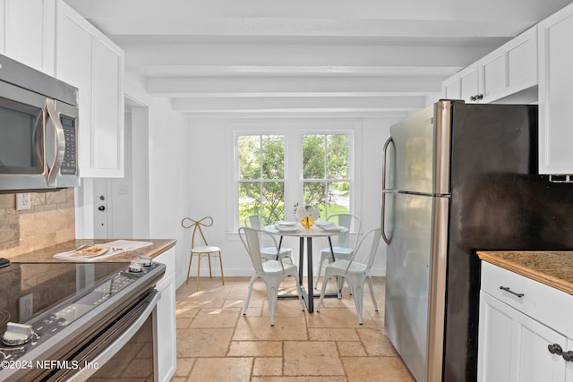 kitchen with backsplash, white cabinets, beam ceiling, and appliances with stainless steel finishes