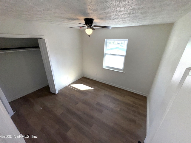 unfurnished bedroom with a closet, ceiling fan, a textured ceiling, and dark hardwood / wood-style flooring